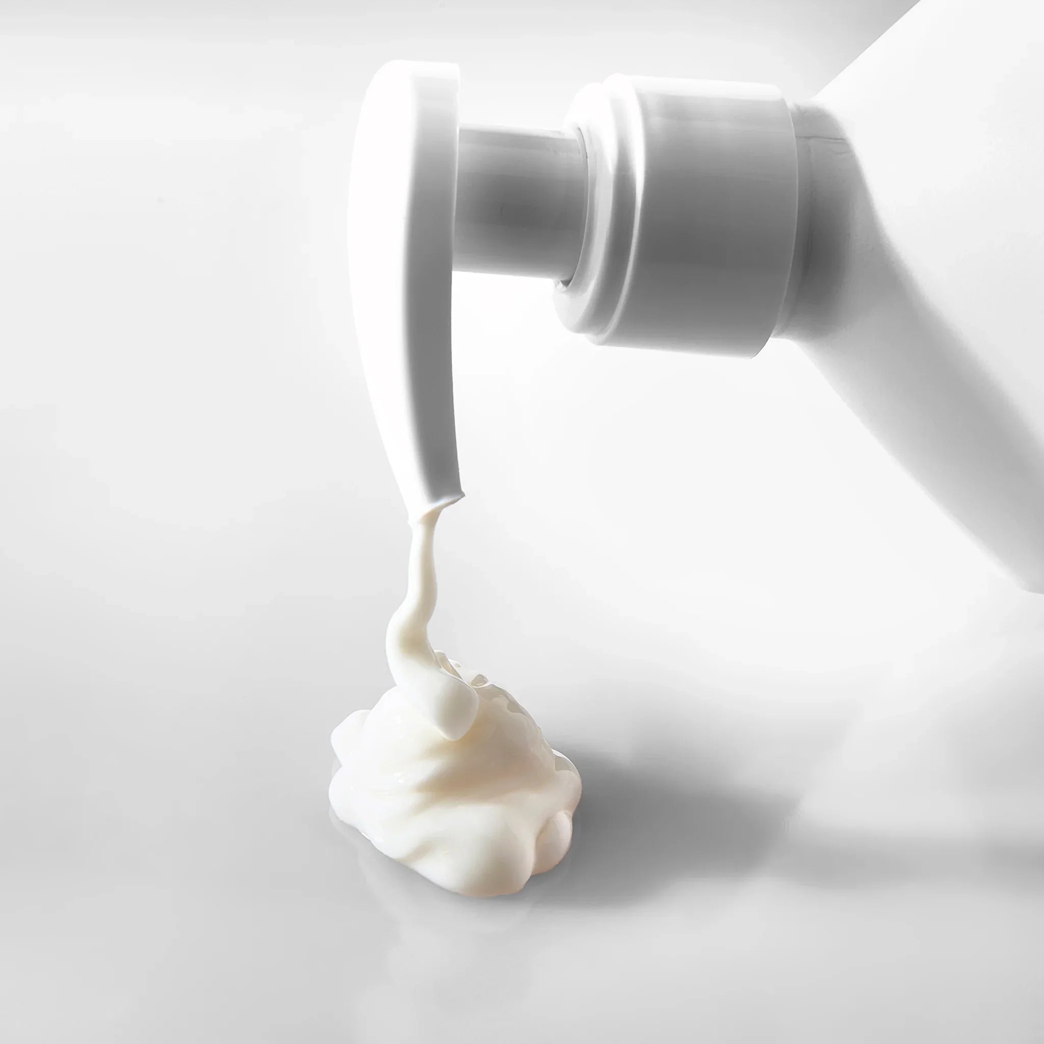 Dettaglio pompa erogatrice di crema corpo idratante bianca con consistenza ricca e densa