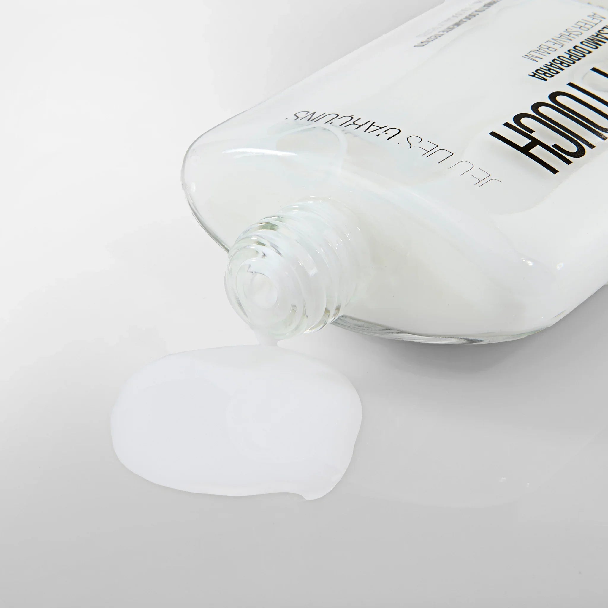 Crema dopobarba bianca versata da tubo trasparente su superficie bianca