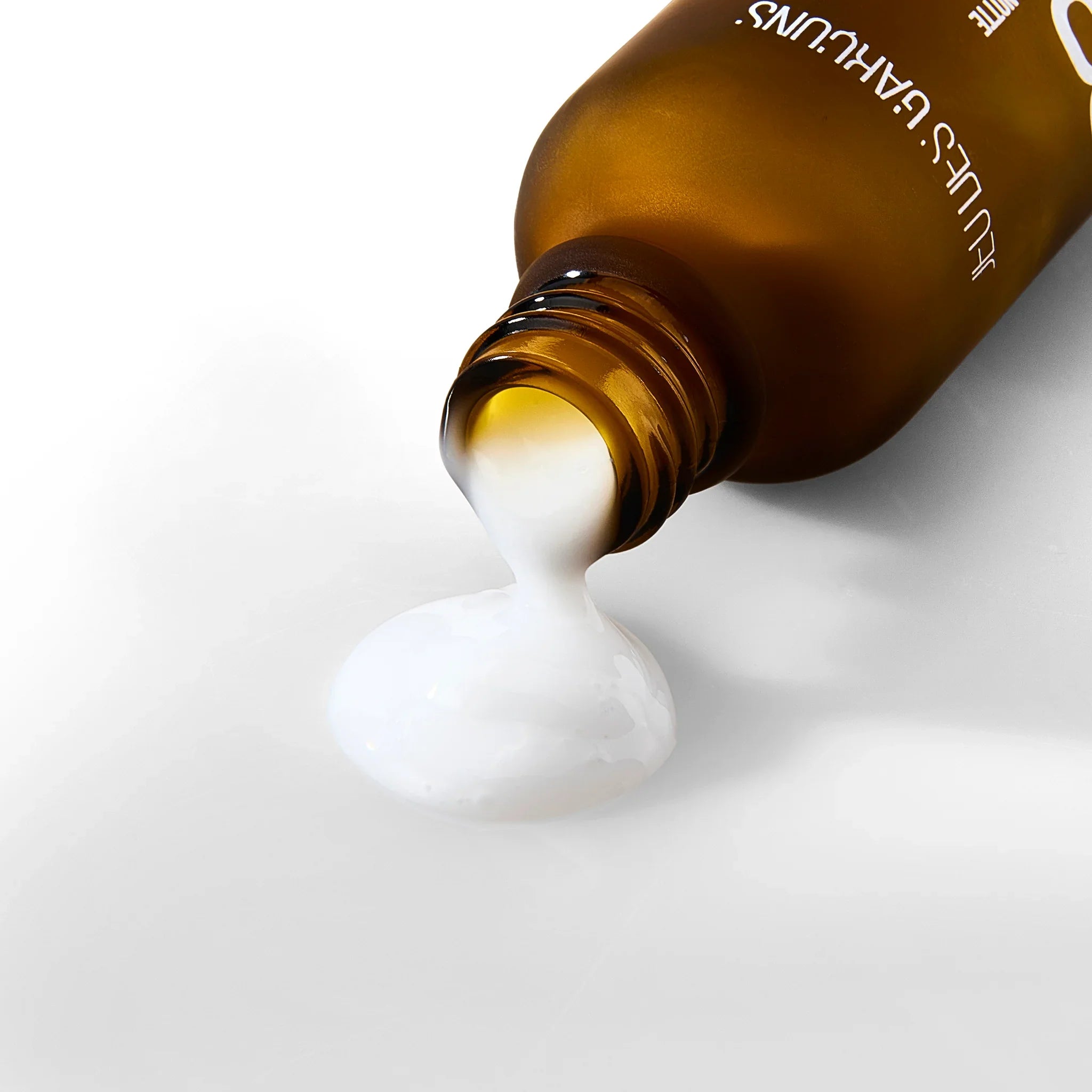 Flacone marrone da cui fuoriesce una crema bianca densa su sfondo bianco, skincare viso